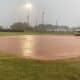 Rains soak the field at the Ada Softball Complex while Clinton coaches sit in the dugout during a delay in the Bi-District contest between the host Lady Cougars and the Lady Reds. The game was postponed until Saturday with Ada on top 3-0 and still batting with one out in the bottom of the second inning.