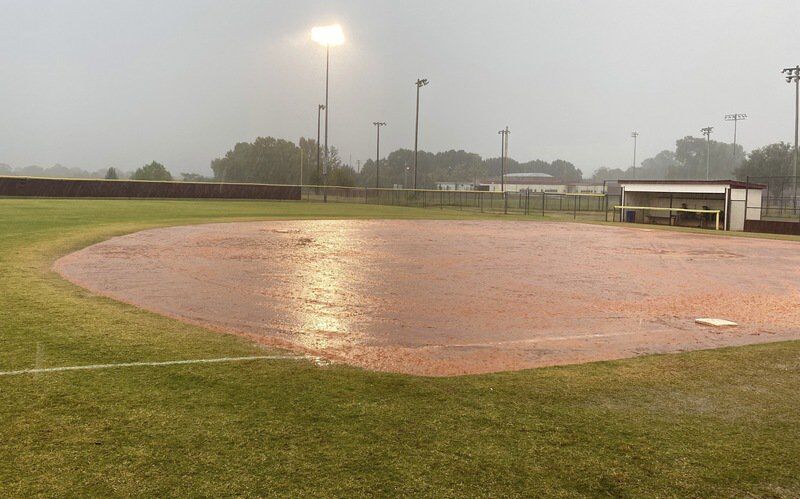 Rains soak the field at the Ada Softball Complex while Clinton coaches sit in the dugout during a delay in the Bi-District contest between the host Lady Cougars and the Lady Reds. The game was postponed until Saturday with Ada on top 3-0 and still batting with one out in the bottom of the second inning.